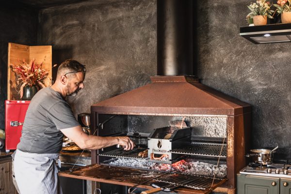 man grilling food using a Braaimaster barbecue or grill setup.